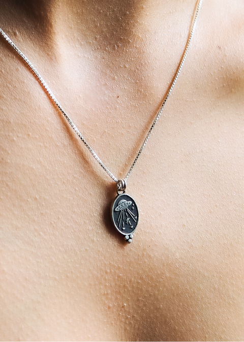 Necklace with a pendant on a person's neck against a neutral background